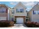 Charming two-story townhome featuring a one car garage, gray shutters, and manicured shrubs at 5665 Terremont Cir, Norcross, GA 30093