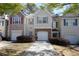 Charming two-story townhome featuring a one car garage, gray shutters, and manicured shrubs at 5665 Terremont Cir, Norcross, GA 30093