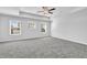 Spacious bedroom featuring tray ceiling, ceiling fan, and abundant natural light from three windows at 4101 Fulson Dr, Lilburn, GA 30047