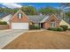 Charming one-story brick home featuring manicured landscaping, a two-car garage, and a welcoming front lawn at 661 Towering Pine Se Trl, Lawrenceville, GA 30045