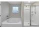 Bright bathroom featuring white bathtub and glass enclosed shower with wall mounted shower head at 8819 Sibella Ct, Lithia Springs, GA 30122