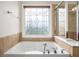 Soaking tub is surrounded by decorative tile and includes a window with privacy glass at 5104 Leeshire Se Trl # 64, Atlanta, GA 30339