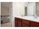 A bathroom is completed with double vanity, white counter tops, cherry cabinets, and a large mirror at 5104 Leeshire Se Trl # 64, Atlanta, GA 30339