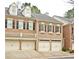 Two-story brick townhome featuring a symmetrical facade, dormer windows, and individual garages at 4703 Legacy Cove Ln, Smyrna, GA 30126