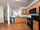 Well-lit kitchen with sleek black appliances, wood cabinets, and an open layout to the living area at 2192 Landing Walk Dr, Duluth, GA 30097