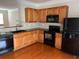 Well-lit kitchen featuring wooden cabinets, black appliances, and hardwood floors at 2192 Landing Walk Dr, Duluth, GA 30097