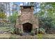 Outdoor brick fireplace with an arched opening for a rustic and cozy outdoor space surrounded by lush landscaping at 105 Weatherford Pl, Roswell, GA 30075