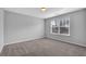 Bright bedroom featuring gray walls, plush carpeting, a ceiling light, and a large window at 3490 Buffington Ln, Cumming, GA 30040