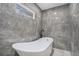 Bathroom featuring modern freestanding tub, gray marble tile, and a window at 1934 Pinedale Pl, Decatur, GA 30032