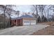 Three-car garage with spacious driveway and wooded backdrop at 1050 Wiley Bridge Rd, Woodstock, GA 30188