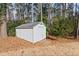 Backyard storage shed with double doors and small wood ramp surrounded by natural landscape with tall trees at 1579 Howell Highlands Dr, Stone Mountain, GA 30087