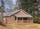 Charming home featuring wood siding, a metal roof, and a cozy front porch, nestled in a natural setting with mature trees at 2595 Poplar Ln, Cumming, GA 30041