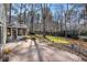 Spacious backyard with a brick patio, green grass, and a view of the wooded lot at 450 Surveyors Pt, Suwanee, GA 30024