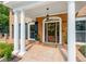 Brick front porch with columns, a wooden door, and potted plants at 1195 Old Woodbine Rd, Atlanta, GA 30319