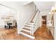 Elegant staircase with hardwood floors and white railings, view of dining room and kitchen at 1195 Old Woodbine Rd, Atlanta, GA 30319