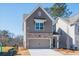 Exterior view of a two-story home features a brick and siding exterior, two-car garage, and yard at 261 Dahlia Dr, Woodstock, GA 30188