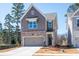 Two-story home features a brick and siding exterior, two-car garage, and a well-maintained front lawn at 261 Dahlia Dr, Woodstock, GA 30188