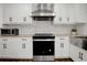 Updated kitchen featuring stainless steel appliances, modern range hood, white cabinets, and hexagon backsplash at 2622 Marcia Dr, Lawrenceville, GA 30044