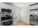 Bright kitchen featuring stainless steel appliances, white cabinetry, and refinished hardwood floors at 2409 Swallow Se Cir, Atlanta, GA 30315