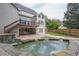 Large backyard featuring stone patio, hot tub, lush landscaping, and stairs to an upper deck at 1901 Shelburne Cv, Marietta, GA 30068