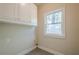 A clean laundry room with overhead cabinets and a window for natural light at 1901 Shelburne Cv, Marietta, GA 30068