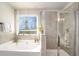 Bright bathroom featuring a soaking tub beneath a window and a glass-enclosed shower at 366 Cherryhill Ln, Woodstock, GA 30188