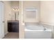 Luxurious soaking tub and vanity in a bright bathroom with tile flooring, granite counters, and natural light at 231 Haney Rd, Woodstock, GA 30188