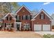 Brick two-story house with a three-car garage and manicured lawn at 115 Parkside Close, Alpharetta, GA 30022