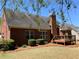 Manicured backyard with lush grass, a brick home exterior, and a wooden deck at 517 Mary Margaret Walk, Loganville, GA 30052