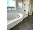 Bright bathroom featuring a soaking tub, a glass enclosed shower, and a large window at 722 Crossroad Ct, Powder Springs, GA 30127