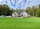 Brick house with large green lawn, driveway, and wooded area in background at 5710 Breitling Dr, Cumming, GA 30028