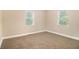 A bright bedroom with neutral walls and carpet has two windows letting in ample natural light at 118 Strickland St, Fairburn, GA 30213