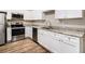 Well-lit kitchen boasts stainless steel appliances, granite counters, and pristine white cabinets, complemented by wood-look flooring at 118 Strickland St, Fairburn, GA 30213