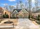 Two-story home with stone and brick facade, attached two-car garage, green lawn and mature trees at 1545 Camden Cove Dr, Cumming, GA 30040