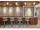 Stylish bar area with sleek stools, a dark countertop, wood paneling, and a modern artwork display, perfect for socializing at 2575 Peachtree Ne Rd # 6G, Atlanta, GA 30305