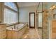 Bright bathroom featuring a soaking tub and glass-enclosed shower with travertine tile at 45 Kinloch Ct, Covington, GA 30014