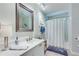 Well-lit bathroom featuring a spacious vanity with countertop, framed mirror, and a shower with a white curtain at 8535 Lynn Dr, Cumming, GA 30041