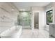 Bright bathroom featuring a glass shower, soaking tub, and marble tile at 2715 Memorial Se Dr, Atlanta, GA 30317