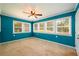 Teal bedroom with carpet flooring, ceiling fan, and multiple windows at 780 Navajo Trl, Covington, GA 30016