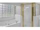Bright bathroom featuring a soaking tub, glass block window, and glass-enclosed shower with gold trim at 1125 Blackshear Dr, Decatur, GA 30033