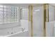 Close-up of bathroom featuring glass block window, soaking tub, and gold trim shower at 1125 Blackshear Dr, Decatur, GA 30033
