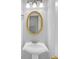 Small powder room featuring pedestal sink, gold mirror, and updated fixtures at 1125 Blackshear Dr, Decatur, GA 30033