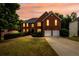 Charming two-story brick home with a well-manicured lawn and a two-car garage at sunset at 1045 Paper Creek Dr, Lawrenceville, GA 30046