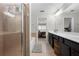 Bright bathroom features a glass enclosed shower, dual vanities, and an open doorway to an adjacent bedroom at 5800 Oakdale Se Rd # 165, Mableton, GA 30126