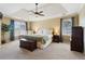 Spacious main bedroom boasts a tray ceiling, a ceiling fan, neutral walls, and cozy carpeting at 1150 Cedar Bluff Sw Trl, Lilburn, GA 30047