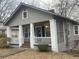 Charming home with a cozy front porch, classic columns, and neutral siding, nestled among mature trees at 1790 Spring Ave, East Point, GA 30344