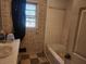 View of an outdated bathroom featuring a sink, tiled walls, tub, and window with dark curtain at 8587 Cumming Hwy, Canton, GA 30115