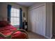 Simple bedroom featuring a window with blinds, double closet, and cozy bed with patterned linens at 1469 Harmony Grove Church Rd, Auburn, GA 30011