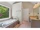 Bright main bathroom features a soaking tub and plenty of natural light from large window at 959 Cedar Falls Sw Ct, Lilburn, GA 30047