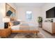 A staged bedroom with a wooden bed frame, modern art and a large television at 5084 Brittany Dr, Stone Mountain, GA 30083